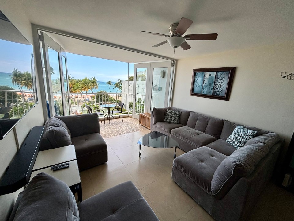 Living room with ocean-view balcony at a Marbella del Caribe apartment in Isla Verde, Puerto Rico